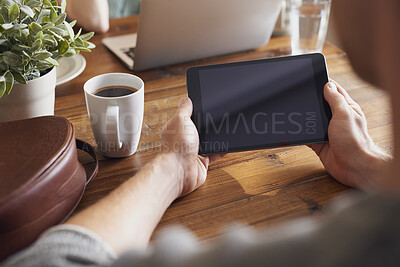 Buy stock photo A man using his digital tablet while sitting at his table