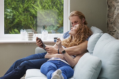 A couple relaxing on the couch together using a credit card to make online purchases