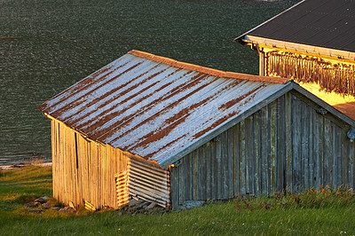 Buy stock photo Wooden structure on an open field by the ocean. An old, dilapidated building on a field of grass in nature 