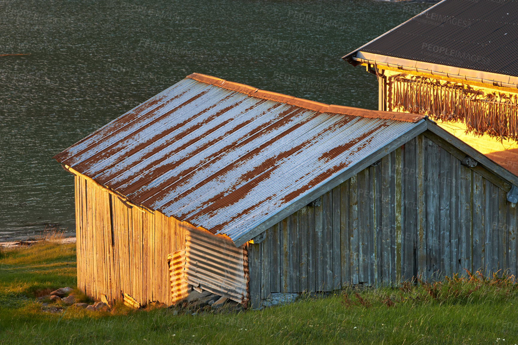 Buy stock photo Wooden structure on an open field by the ocean. An old, dilapidated building on a field of grass in nature 