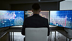 Rear view of businessman using multiple monitors and trading on the stock market in a financial crisis. Trader online in a bear market with stocks crashing. Market crash and economy depression or failure
