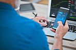 Closeup of a businessman using a phone and laptop, trading on the stock market in a financial crisis. Online trader with computer in a bear market. Virtual or remote work in market and economy crash