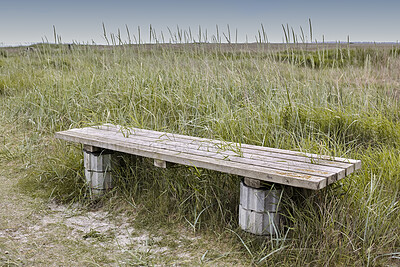 Buy stock photo An old wooden bench in an open field outside with a field with lush green grass in a valley background. Find a quiet place to enjoy the beauty of nature. The woods can be a peaceful and tranquil place when you need to be alone