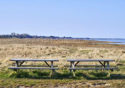 Buy stock photo Two wooden benches on a field overlooking the ocean. A quiet place to enjoy nature and the peace it has to offer. Find tranquility amongst the green grass and views of the ocean. Beauty in nature