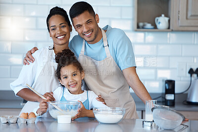 Young mixed race happy family smiling while cooking a meal together in the kitchen at home. Little hispanic girl helping her loving parents bake a healthy snack at home