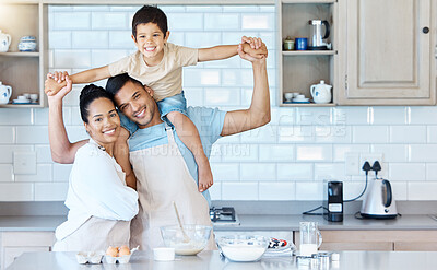 Buy stock photo Portrait of happy young mixed race couple bonding with their adorable son in a home kitchen while baking. Hispanic husband carrying a child on his shoulders while his wife embraces him. Time together