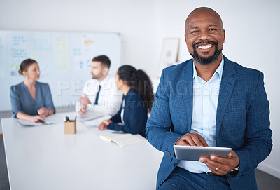 Portrait of smiling confident african american businessman in boardroom using digital tablet. Diverse group of businesspeople in meeting and working behind black manager. Browsing online on technology