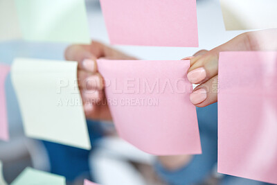 Buy stock photo Closeup of unknown business woman using sticky notes on a transparent board to brainstorm in the office. Caucasian professional sticking a note on a visual aid while planning a strategy with ideas
