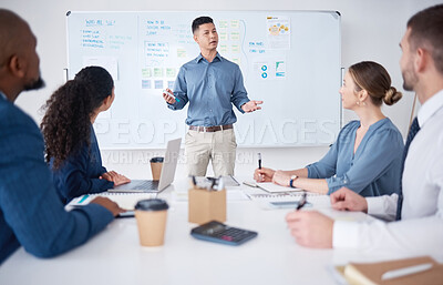 Serious mixed race business manager training and teaching team of colleagues in boardroom. Hispanic businessman using a whiteboard to talk and explain to diverse group of businesspeople in workshop