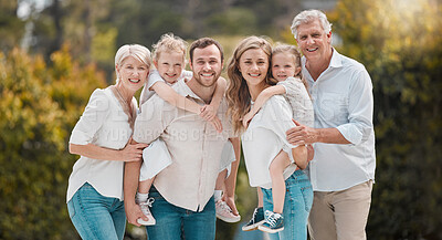 Portrait of multi-generation family standing together. Extended caucasian family smiling while spending time together at the park on a sunny day. Family with two children, parents and grandparents