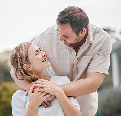 A loving happy mature caucasian husband and wife staring into each other eyes and smiling in a loving way. A man holding his wife\'s hand and embracing her with affection and intimacy outside in a backyard