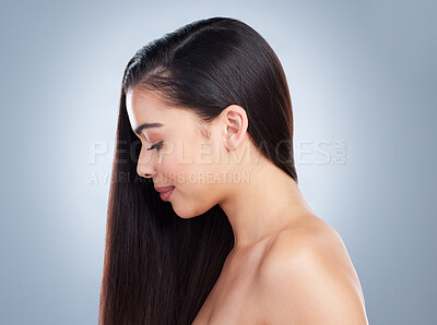 Profile of a beautiful young brunette woman with healthy hair and skin posing against a grey studio background. Young woman posing with her hair to the side.