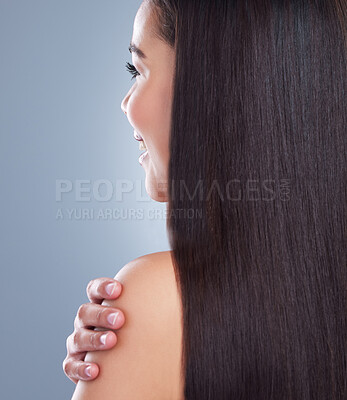 Close up of a young woman with beautiful long smooth hair touching her shoulder. Young mixed race woman with luxurious straight and shiny brown hair. Healthy hair against studio background