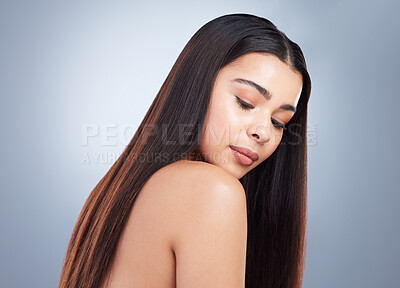 Beautiful young woman with shiny brown and straight long hair. Young girl looking down at her shoulder and showing off healthy-looking hair