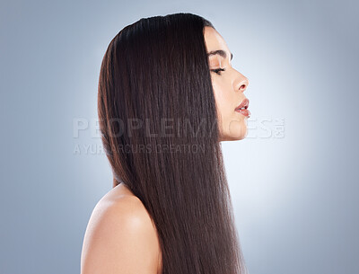 Profile view of a beautiful brown-haired girl with smooth and shiny hair posing against a grey background. Young brunette woman with beautiful long straight hair