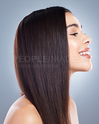 Profile view of a beautiful brown-haired woman with smooth and shiny hair posing against a grey background. Happy young brunette woman with beautiful long straight hair