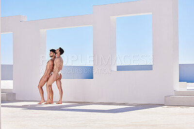 Two nude caucasian muscular gay men standing passionately outdoors on a sunny day. Two young handsome homosexual males in love exposing their naked natural bodies outside against a clear blue sky