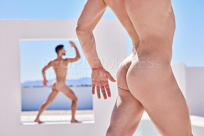 Body of muscular, naked caucasian man posing outside. Butt of nude male model, posing in front of a white wall. Strong, sensual man flaunting toned body standing in a cut out wall against a blue sky
