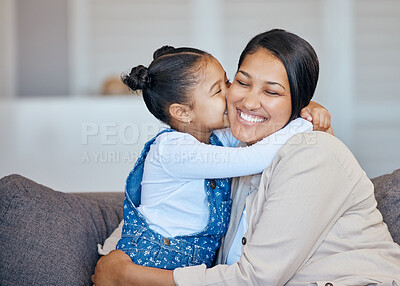 Adorable little mixed race girl kissing her mom on cheek while bonding at home. Loving, caring and affectionate mother and daughter spending quality time together. Woman being spoiled on mother\'s day