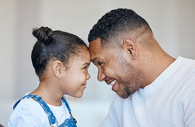Mixed race father and daughter staring at each other with heads touching face to face while bonding together at home. Caring single dad having fun spending quality time with his adorable little girl