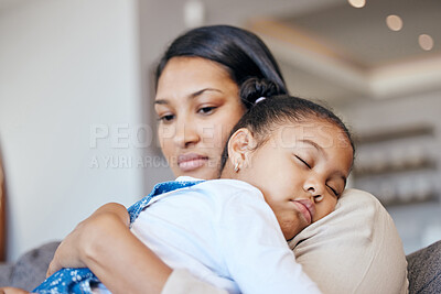 Young mixed race mother looking worried while holding her daughter while she sleeps and sitting on the couch in the lounge at home. Little girl looking comfy while sleeping and hugging her mom