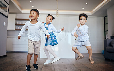 Three mixed race young children dancing and having fun in the living room at home. Siblings, two brothers and a sister, having a dance contest in their lounge. Fun, happy and carefree times together