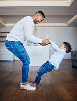 Little boy standing on dad\'s feet and sharing a dance. Playful dad and son having fun together at home. Cheerful man teaching his son to dance
