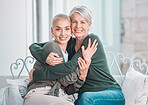 Cheerful senior mother hugging adult daughter. Loving caucasian mom giving her daughter a hug while sitting on a chair together at home. Mature woman looking happy to visit her daughter
