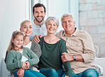 Cute little girl sitting on the couch together with family. Happy child sitting with her parents and grandparents at home. Caucasian family smiling while relaxing together during a visit