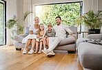 Fullbody young smiling caucasian family sitting on the couch together and bonding in a home lounge on a weekend. Mother and father sitting with children on a sofa 