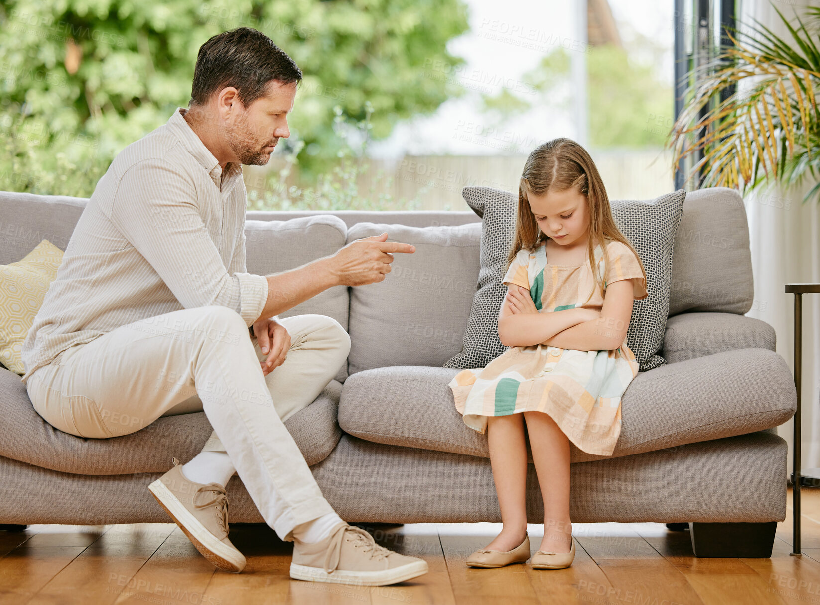 Buy stock photo Pointing, scold and father with child on a sofa in the living room for naughty behavior at home. Upset, angry and young strict dad talking to sad girl kid on the couch in lounge at modern house.