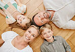 Happy caucasian family of four from above lying on wooden floor at home. Smiling carefree mature parents with their two little kids. Adorable young girl and boy bonding with their loving mom and dad
