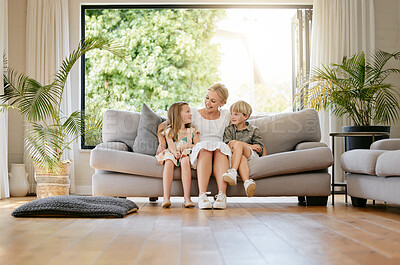 Buy stock photo Fullbody of a young cheerful content mother enjoying relaxing time with her daughter and son sitting on the couch together at home. Little brother and sister bonding with their mom on the weekend