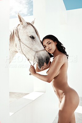 Full Body portrait of beautiful mixed race woman posing nude while standing next to a white horse and holding the reins outdoors. Sexy hot hispanic model showing her naked body with white stallion. Nudist feeling sensual, seductive, free on a mare