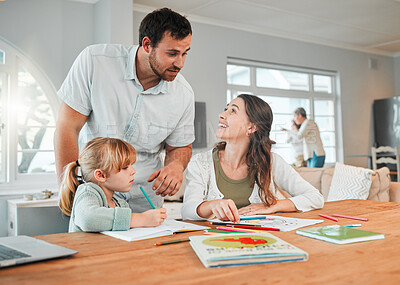 Buy stock photo Adorable little caucasian girl sitting at table and doing homework while her mother helps her. Beautiful happy young woman pointing and teaching her daughter at home while her husband watches on