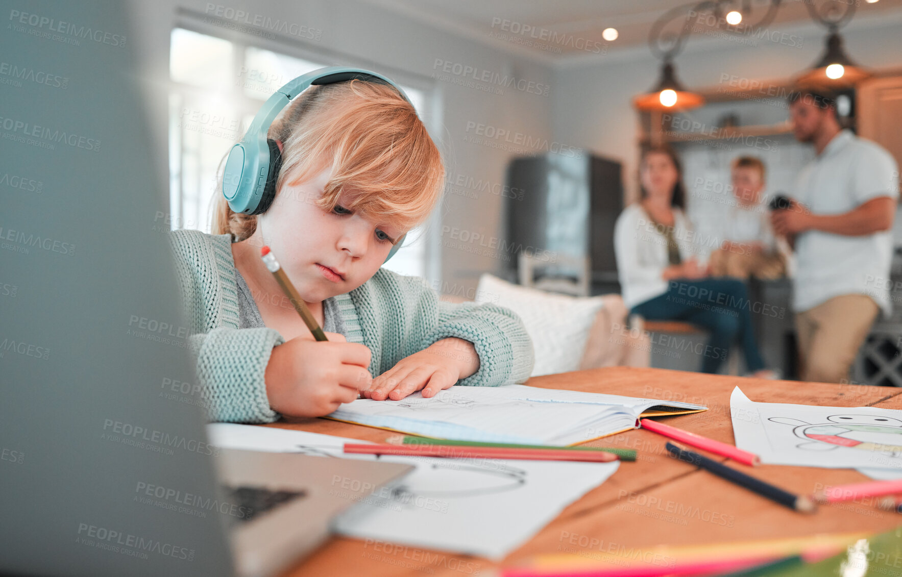 Buy stock photo Closeup of a cute caucasian little brunette girl wearing wireless headphones while holding a pencil and being creative by drawing in a book at home with her family in the background. Young girl listening to music with her wireless device with focusing on homework