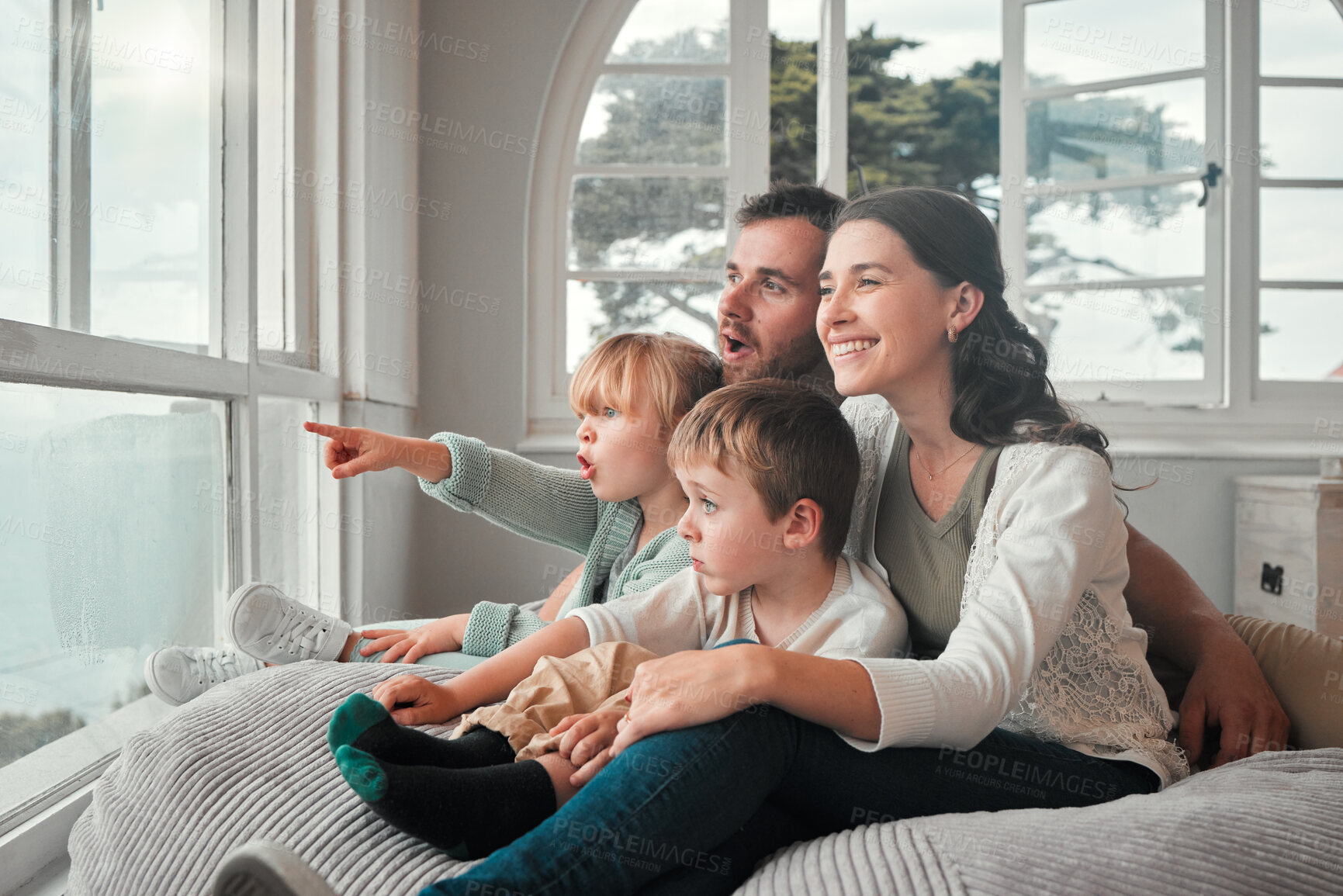 Buy stock photo Parents, children and relax by window, happy and pointing with view, bonding and love with in family house. Father, mother and kids with conversation, talking and smile on bean bag, wow face and home