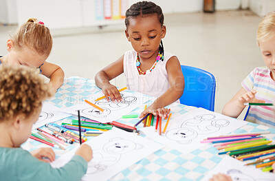Diverse group of children sitting at a table and colouring at pre-school or kindergarten. Group of kids with colourful pencils and pictures