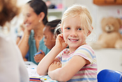 A happy little girl getting an education in primary school and learning during a lesson. Portrait of a cute, caucasian female child student sitting at a desk in class and looking at the camera
