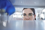 Closeup of unknown caucasian medical scientist wearing glasses and looking at a medicine vial in a laboratory. Healthcare pathologist discovering a cure in a clinic. Controlling diseases with science