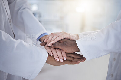 Diverse group of doctors standing with hands stacked to motivate one another. Group of medical professionals collaborating, cheering together in a meeting. Hands of medical colleagues huddled together