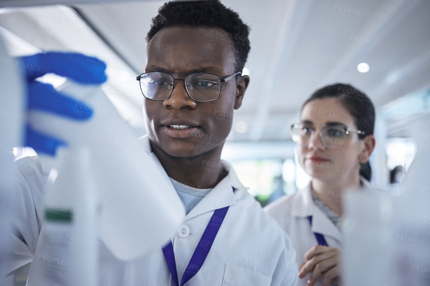 Buy stock photo People, scientist or checking inventory in lab for experiment, sample bottle or chemical. Young man and woman or team in science research, stock check or reading product information at laboratory