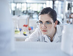 One young caucasian medical scientist wearing spectacles and looking at a medicine vial in a laboratory. Healthcare pathologist discovering a cure in a clinic. Control diseases with science