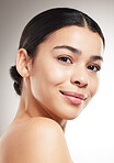Face of a happy young beautiful mixed race woman smiling and posing against a grey studio background. Confident hispanic female posing against a background