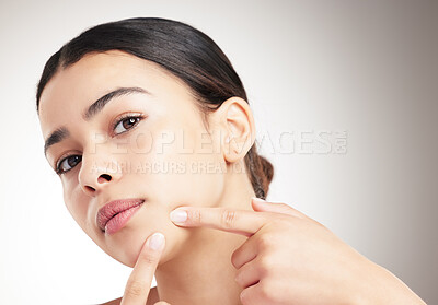 Buy stock photo Beautiful young woman popping a pimple standing against a grey studio background alone. One female touching her face while standing against a background