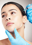 Portrait of a young mixed race woman getting botox against a grey studio background. Hispanic female taking care of her skin with a checkup against a background