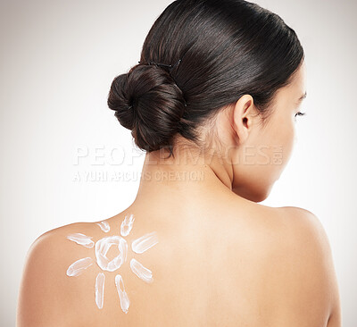 Buy stock photo Back of a beautiful woman showing her applying cream on her shoulder posing against a grey studio background. Skincare is important. Protection from the sun