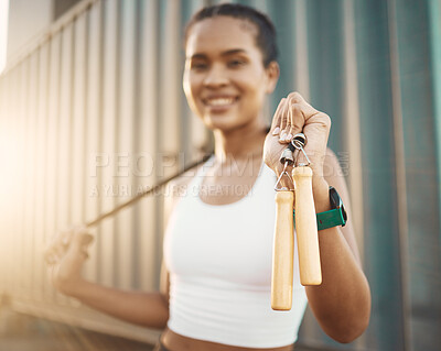 Closeup of one fit young hispanic woman holding a jumping rope for skipping while exercising in an urban setting outdoors. Happy athlete holding a jumprope for cardio workout and warmup