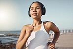 Close up of fit young female athlete in sportswear wearing wireless headphones and listening to music while out for a run along the promenade. Exercise is good for you health and wellbeing