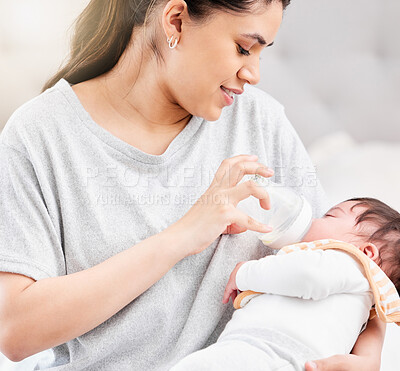 Young hispanic mother feeding her newborn baby a milk bottle and bonding with her. Little baby asleep in her mother\'s arms in her bedroom. Small, tiny baby drinking milk and falling asleep